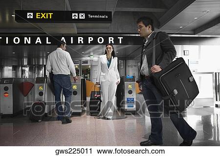Three people walking at an airport View Large Photo Image Stock Image - Three people walking at an airport. Fotosearch