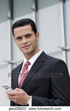 Portrait of a businessman holding a mobile phone and smiling View Large Photo Image Stock Image - Portrait of a businessman holding a mobile phone and smiling. Fotosearch