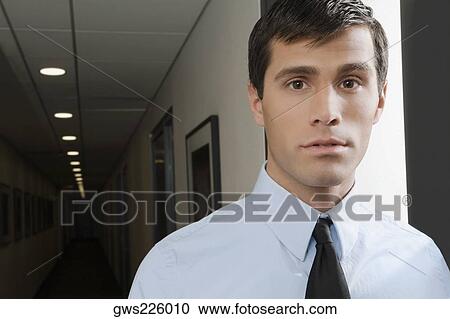 Stock Image - Portrait of a businessman standing in a corridor. Fotosearch
