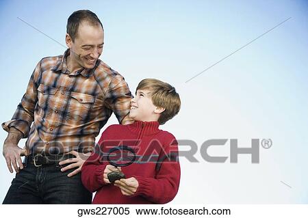 Boy holding a magnifying glass and standing with his father View Large Photo Image Stock Photography - Boy holding a magnifying glass and standing with his father. Fotosearch