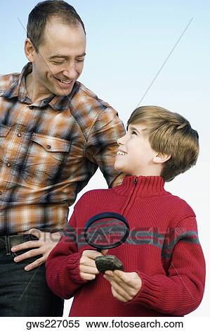 Boy holding a magnifying glass and standing with his father View Large Photo Image Stock Photography - Boy holding a magnifying glass and standing with his father. Fotosearch
