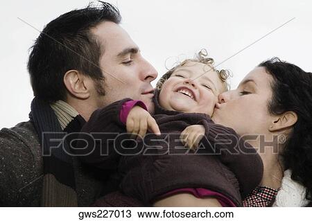 Close-up of a couple kissing their daughter View Large Photo Image Stock Image - Close-up of a couple kissing their daughter. Fotosearch