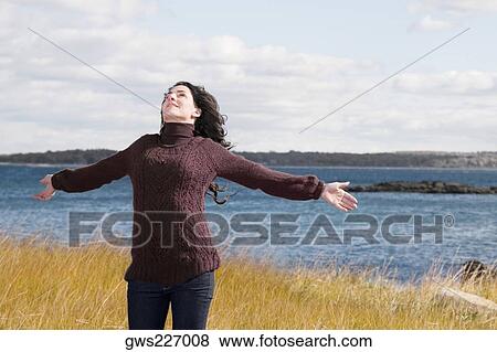 Mature woman standing on the beach with her arms outstretched View Large Photo Image Stock Photo - Mature woman standing on the beach with her arms outstretched. Fotosearch