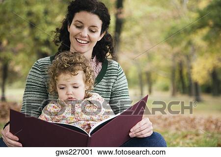 Mid adult woman and her daughter looking at a picture book View Large Photo Image Stock Image - Mid adult woman and her daughter looking at a picture book. Fotosearch