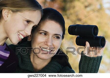 Mid adult woman with her daughter looking through binoculars View Large Photo Image Picture - Mid adult woman with her daughter looking through binoculars. Fotosearch