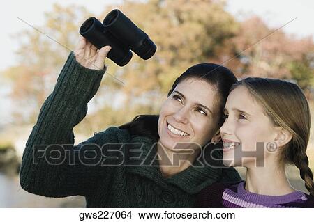 Mid adult woman with her daughter looking through binoculars View Large Photo Image Picture - Mid adult woman with her daughter looking through binoculars. Fotosearch