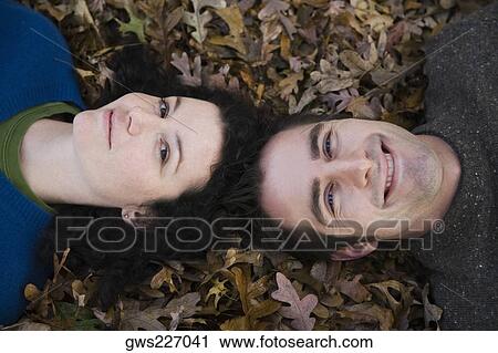 Portrait of a couple lying in a lawn View Large Photo Image Stock Image - Portrait of a couple lying in a lawn. Fotosearch