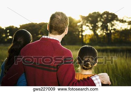 Rear view of a mid adult couple standing with their daughter View Large Photo Image Stock Photo - Rear view of a mid adult couple standing with their daughter. Fotosearch