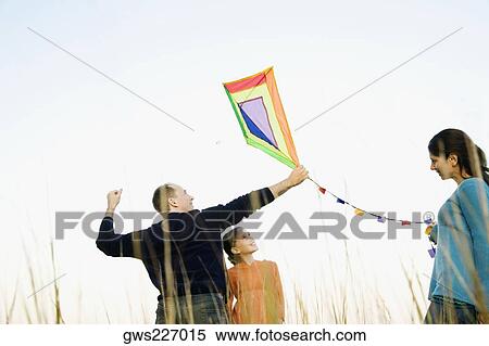 Stock Photography - Rear view of a mid adult man with his family flying a kite. Fotosearch