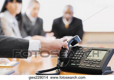 Close-up of a businessman's hand holding a conference phone receiver View Large Photo Image Picture - Close-up of a businessman's hand holding a conference phone receiver. Fotosearch