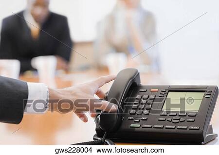 Close-up of a businesswoman's hand reaching to a conference phone receiver View Large Photo Image Picture - Close-up of a businesswoman's hand reaching to a conference phone receiver. Fotosearch