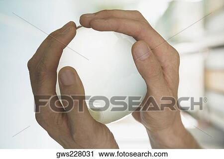 Stock Image - Close-up of a person's hand holding a globe. Fotosearch