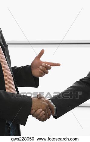 Close-up of two businessmen shaking hands at an airport View Large Photo Image Stock Image - Close-up of two businessmen shaking hands at an airport. Fotosearch