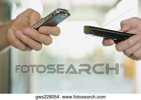 Picture - Close-up of two people using their mobile phones. Fotosearch