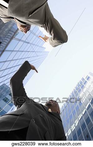 Low angle view of two businessmen giving high-five and smiling View Large Photo Image Stock Photo - Low angle view of two businessmen giving high-five and smiling. Fotosearch