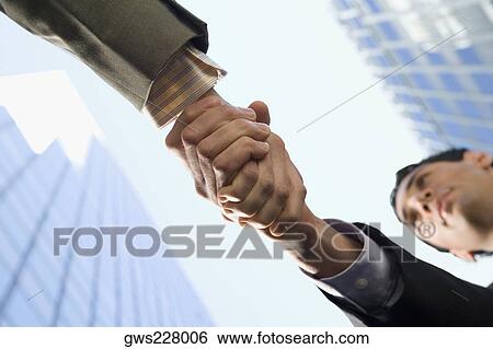 Low angle view of two businessmen shaking hands View Large Photo Image Stock Photograph - Low angle view of two businessmen shaking hands. Fotosearch