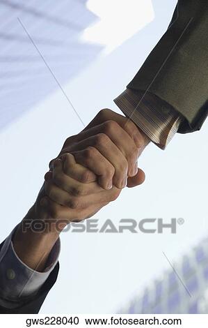 Low angle view of two people shaking hands View Large Photo Image Stock Image - Low angle view of two people shaking hands. Fotosearch