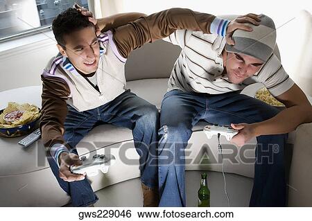 High angle view of two young men playing video game and rough housing View Large Photo Image Stock Photograph - High angle view of two young men playing video game and rough housing. Fotosearch
