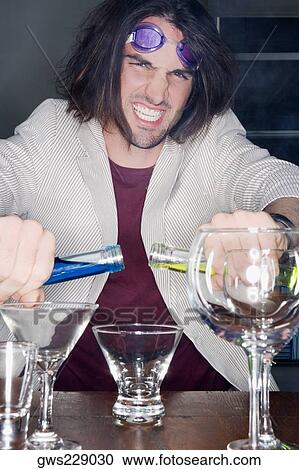 Stock Image - Portrait of a young man making a cocktail. Fotosearch