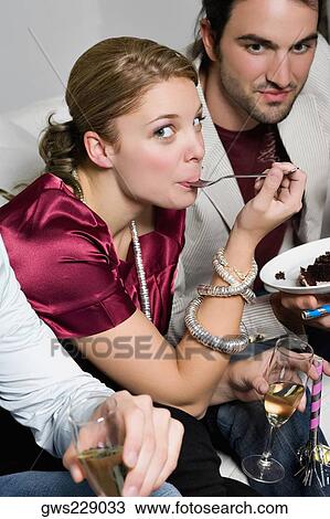 Portrait of a young woman eating cake and sitting with her friends View Large Photo Image Stock Image - Portrait of a young woman eating cake and sitting with her friends. Fotosearch