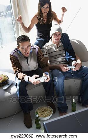 Two young men and a young woman playing video game View Large Photo Image Stock Image - Two young men and a young woman playing video game. Fotosearch