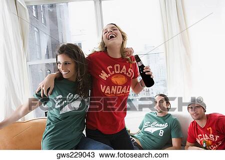 Two young men lying on a couch with two young women drinking beer and dancing View Large Photo Image Stock Image - Two young men lying on a couch with two young women drinking beer and dancing. Fotosearch