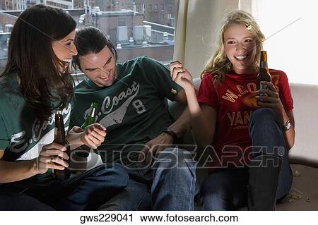 Two young women and a young man holding beer bottles View Large Photo Image Stock Image - Two young women and a young man holding beer bottles. Fotosearch