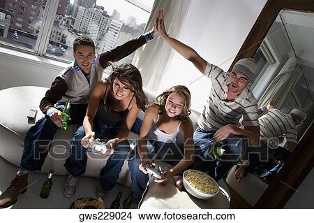 Two young women playing video game and two young men making high five beside them View Large Photo Image Picture - Two young women playing video game and two young men making high five beside them. Fotosearch