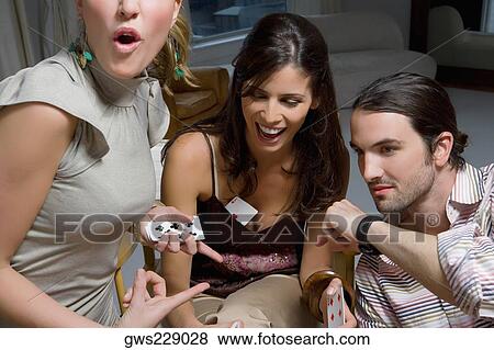 Stock Photo - Two young women with a young man playing cards. Fotosearch