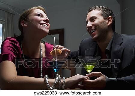 Stock Photo - Young couple drinking cocktail and romancing. Fotosearch