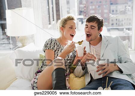 Stock Photography - Young couple eating food with chopsticks. Fotosearch