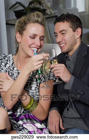 Young couple toasting with champagne flutes and smiling View Large Photo Image Stock Photo - Young couple toasting with champagne flutes and smiling. Fotosearch