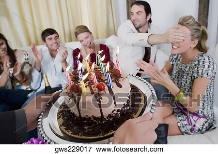 Stock Photo - Young woman celebrating birthday with her friends. Fotosearch