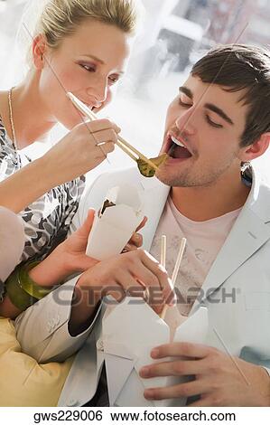 Stock Photograph - Young woman feeding food to a young man. Fotosearch