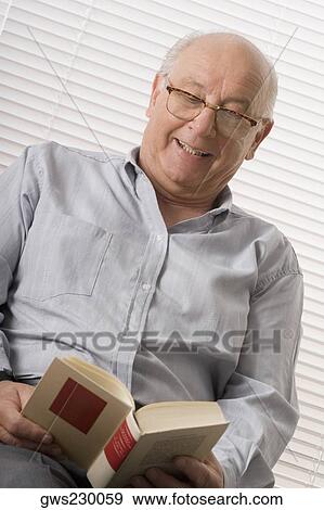 Close-up of a senior man reading a book and smiling View Large Photo Image Stock Photo - Close-up of a senior man reading a book and smiling. Fotosearch
