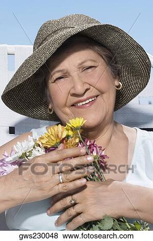 Close-up of a senior woman holding a bunch of flowers and smiling View Large Photo Image Stock Photo - Close-up of a senior woman holding a bunch of flowers and smiling. Fotosearch
