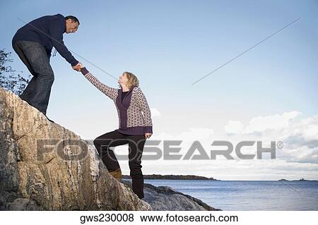 Mature man helping a mature woman to climb a rock View Large Photo Image Stock Photo - Mature man helping a mature woman to climb a rock. Fotosearch