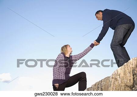 Mature man helping a mature woman to climb a rock View Large Photo Image Stock Photo - Mature man helping a mature woman to climb a rock. Fotosearch