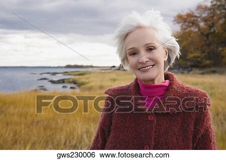 Stock Photograph - Portrait of a senior woman smiling on the beach. Fotosearch