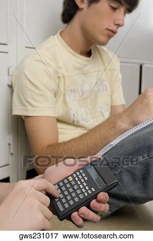 Close-up of a person's hand using a calculator and a young man sitting beside him View Large Photo Image Stock Photo - Close-up of a person's hand using a calculator and a young man sitting beside him. Fotosearch