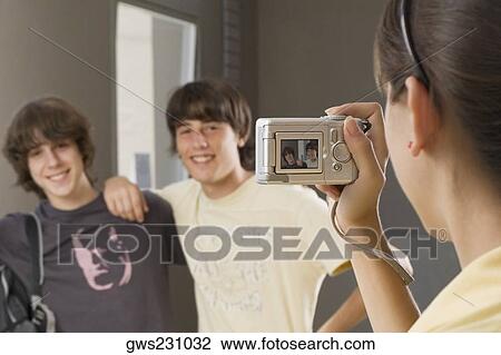 Stock Image - Close-up of a teenage girl taking a photograph of her two friends with a digital camera. Fotosearch