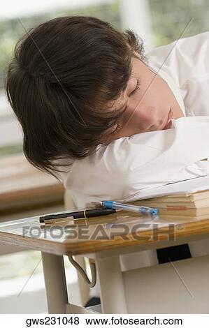 Close-up of a young man sleeping on desk in a classroom View Large Photo Image Stock Photo - Close-up of a young man sleeping on desk in a classroom. Fotosearch