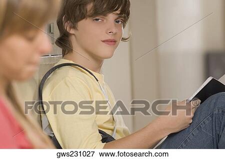 Portrait of a teenage boy studying with his friend sitting beside her View Large Photo Image Stock Photo - Portrait of a teenage boy studying with his friend sitting beside her. Fotosearch