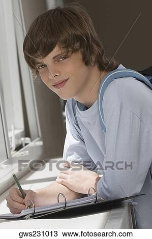 Portrait of a teenage boy writing on spiral notebook and smiling View Large Photo Image Stock Image - Portrait of a teenage boy writing on spiral notebook and smiling. Fotosearch