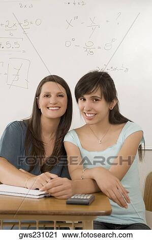 Portrait of a teenage girl and a female teacher sitting in a classroom and smiling View Large Photo Image Stock Image - Portrait of a teenage girl and a female teacher sitting in a classroom and smiling. Fotosearch