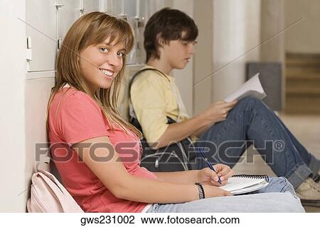 Portrait of a teenage girl leaning against a wall and studying with a teenage boy beside her View Large Photo Image Stock Image - Portrait of a teenage girl leaning against a wall and studying with a teenage boy beside her. Fotosearch