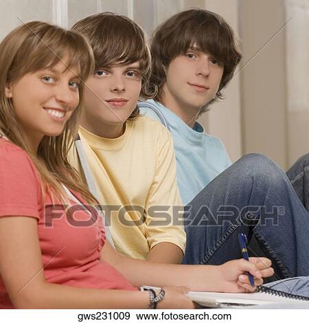 Portrait of a teenage girl smiling with her friends sitting beside her View Large Photo Image Stock Photo - Portrait of a teenage girl smiling with her friends sitting beside her. Fotosearch