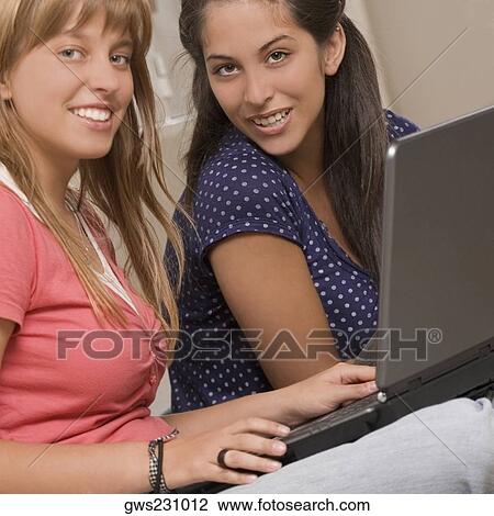 Portrait of a teenage girl using a laptop with her friend sitting beside her View Large Photo Image Stock Image - Portrait of a teenage girl using a laptop with her friend sitting beside her. Fotosearch