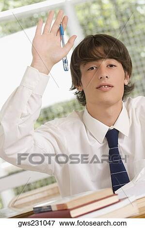 Portrait of a young man raising his hand in a classroom View Large Photo Image Stock Photo - Portrait of a young man raising his hand in a classroom. Fotosearch