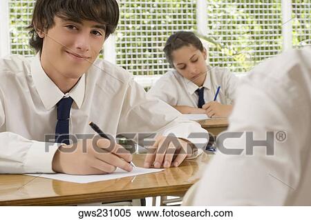 Portrait of a young man writing on paper sheet and smiling with a teenage girl behind him View Large Photo Image Stock Photography - Portrait of a young man writing on paper sheet and smiling with a teenage girl behind him. Fotosearch